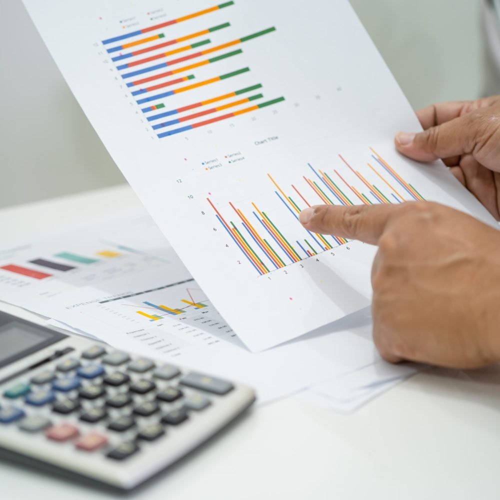 Asian accountant working and analyzing financial reports project accounting with chart graph and calculator in modern office, finance and business concept.